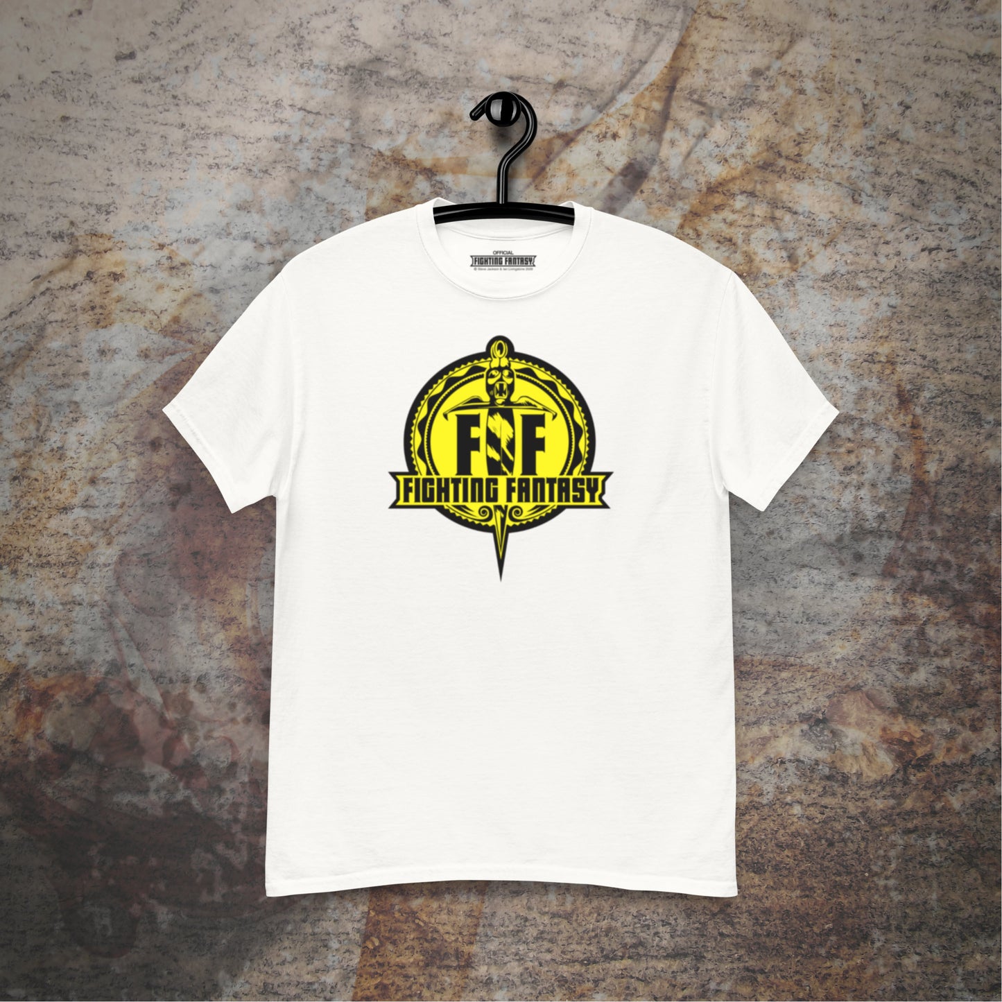 Fighting Fantasy logo design on a white t-shirt hanging in front of a stone wall background.