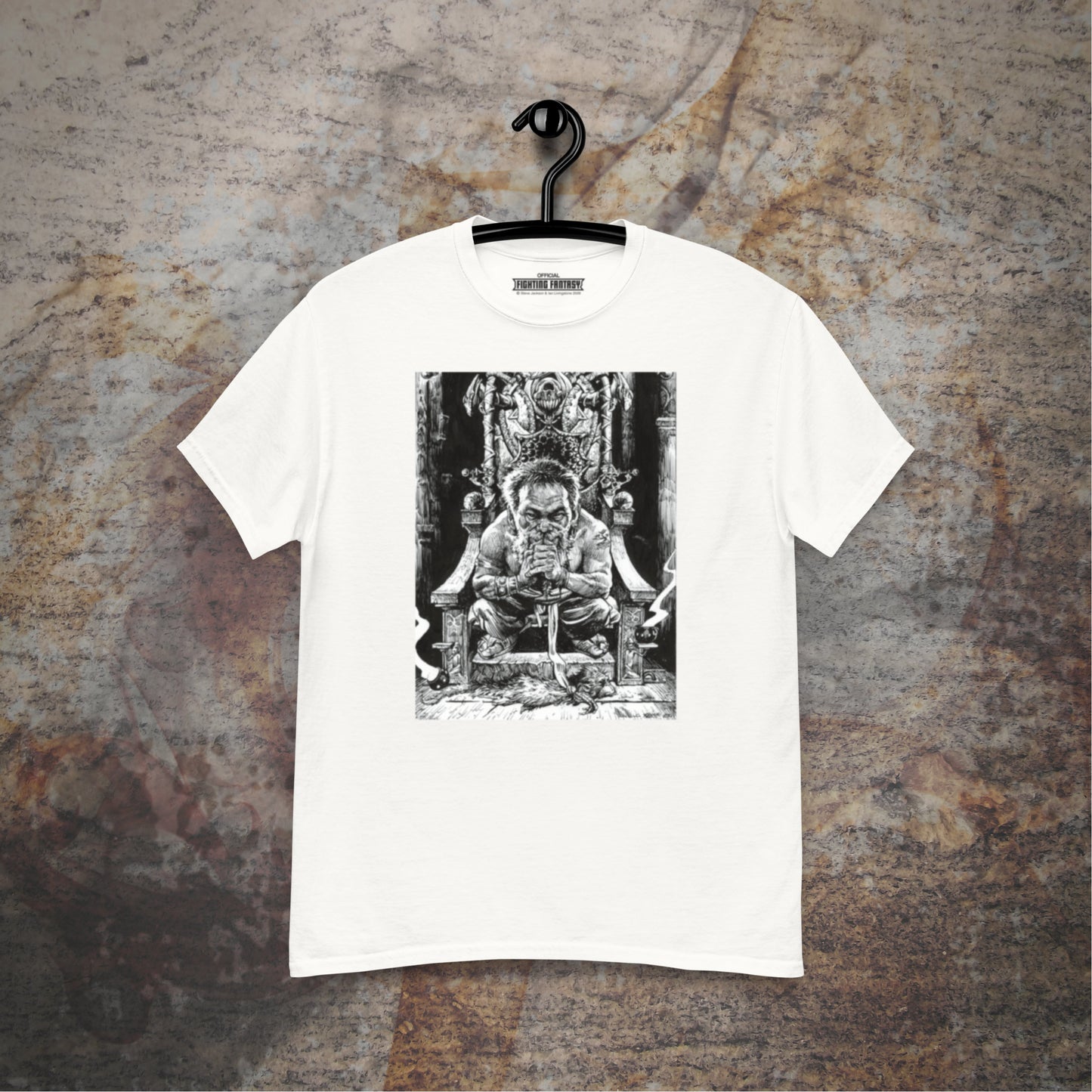 Trialmaster design on a white t-shirt hanging in front of a stone wall background.