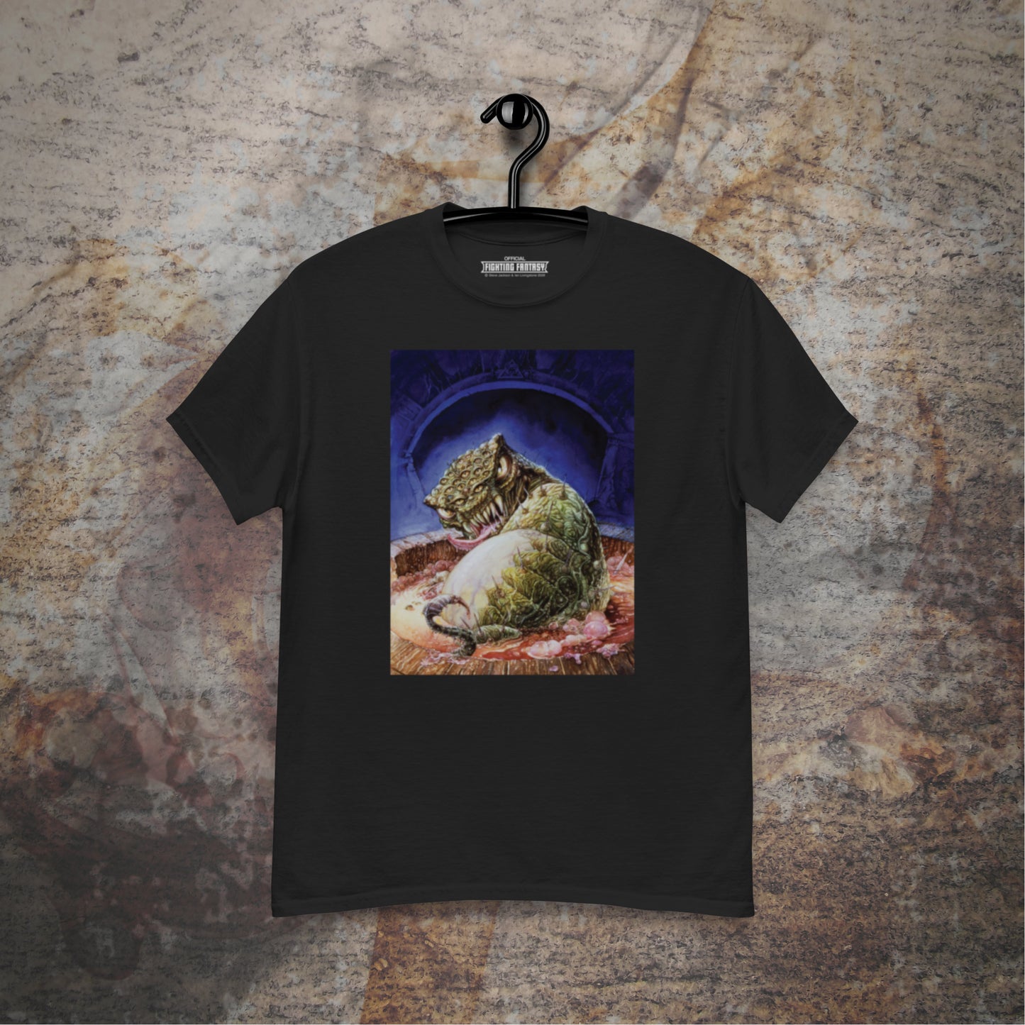 Deathtrap Dungeon design on a black t-shirt hanging in front of a stone wall background.