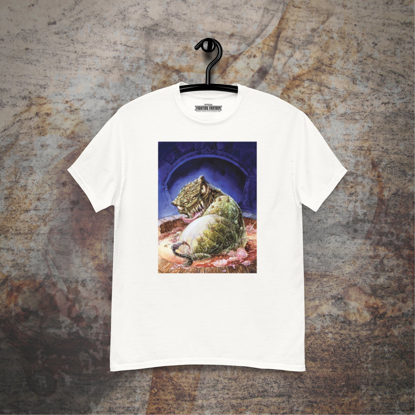 Deathtrap Dungeon design on a white t-shirt hanging in front of a stone wall background.