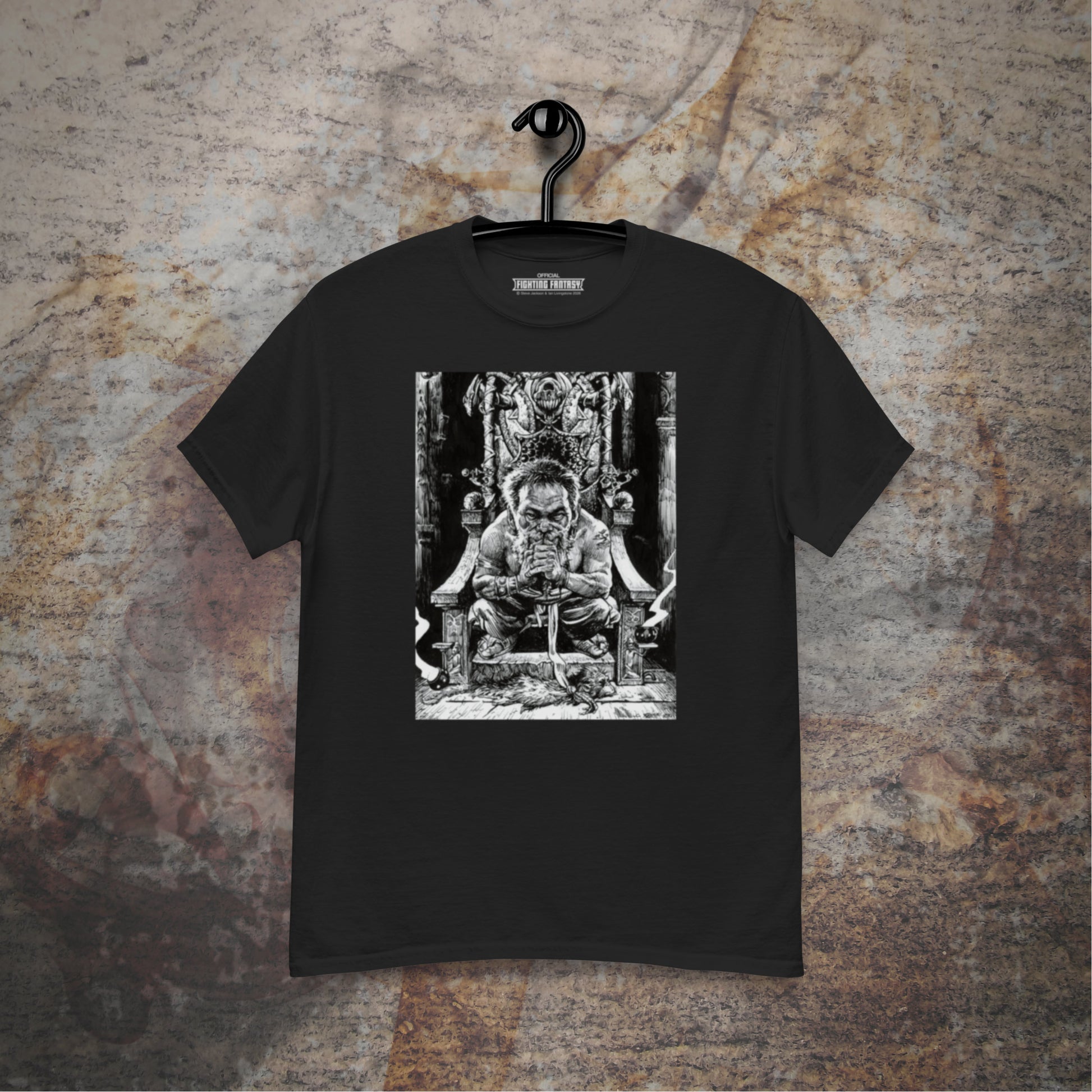 Trialmaster design on a black t-shirt hanging in front of a stone wall background.